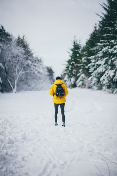 白天背着背包站在雪地上的男人